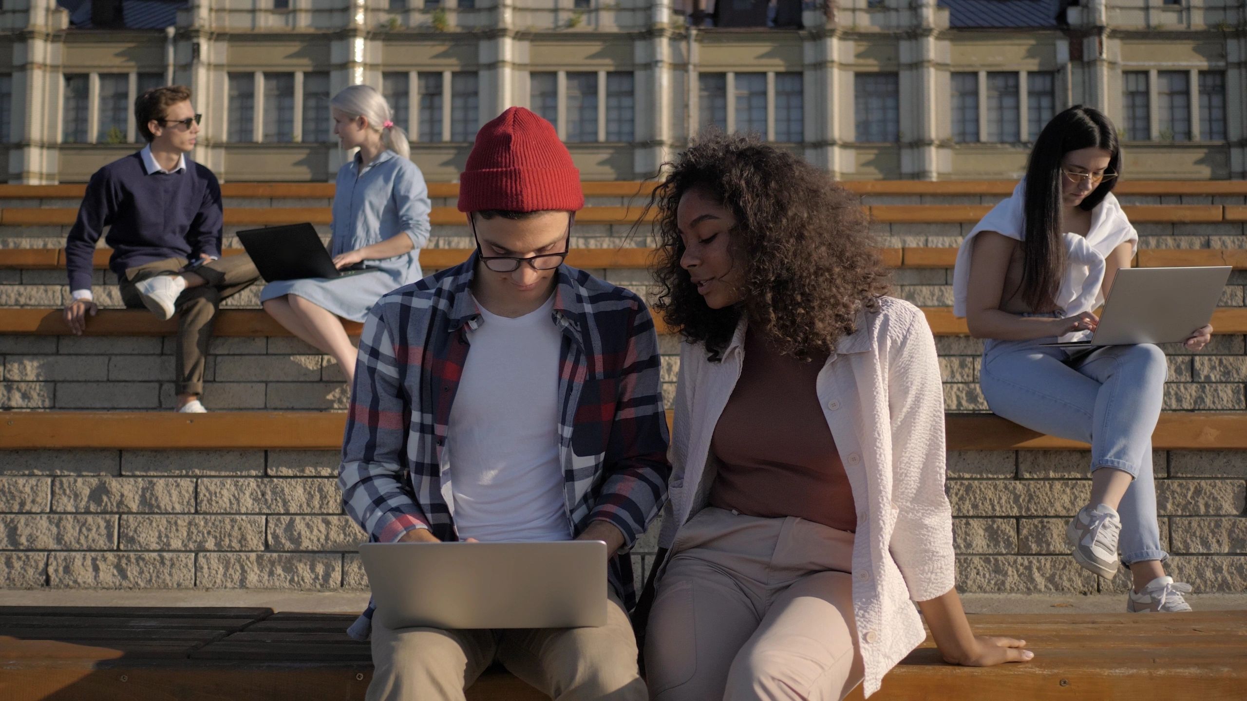 People collaborating with laptops outdoors