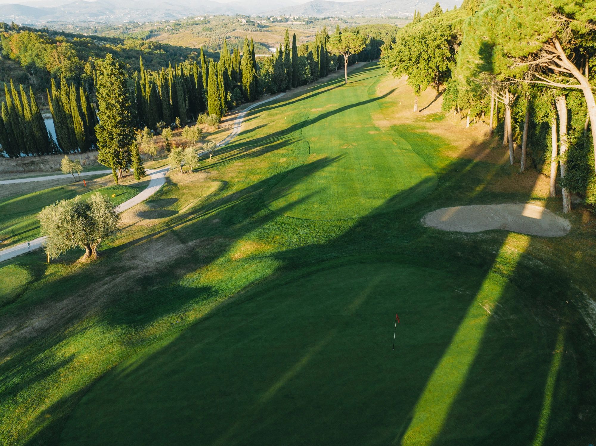 Golf course fairway with sand trap and cypress trees